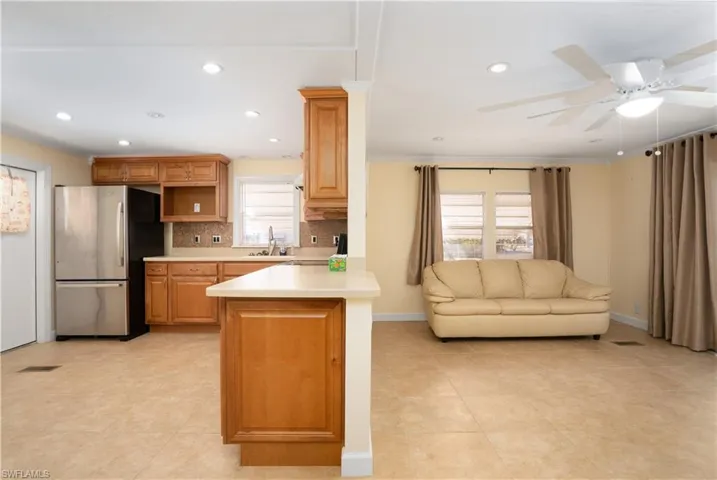 Kitchen with tasteful backsplash, sink, stainless steel fridge, ceiling fan, and kitchen peninsula
