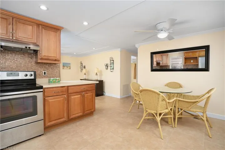 Kitchen featuring ceiling fan, stainless steel electric range oven, decorative backsplash, and light tile patterned floors