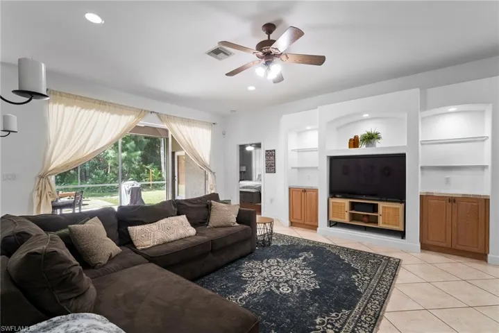 Living room featuring built in features, ceiling fan, and light tile patterned floors