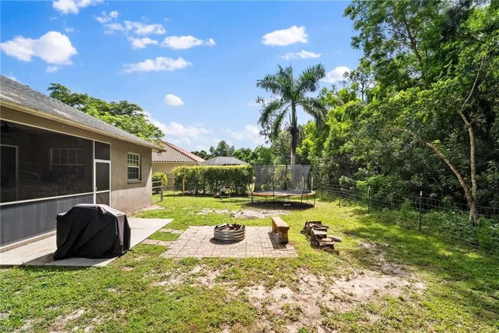 View of yard featuring a fire pit, a sunroom, a trampoline, and a patio area
