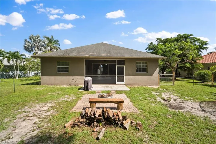 Rear view of property with an outdoor fire pit, a patio area, a yard, and a sunroom