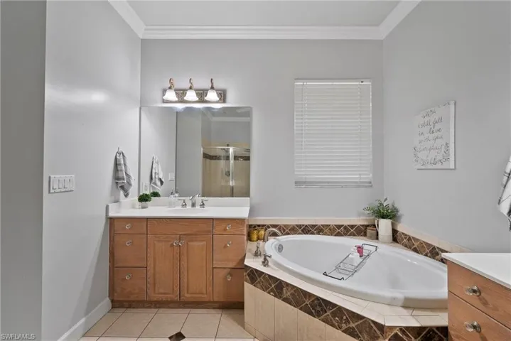 Bathroom with plus walk in shower, tile patterned flooring, ornamental molding, and vanity