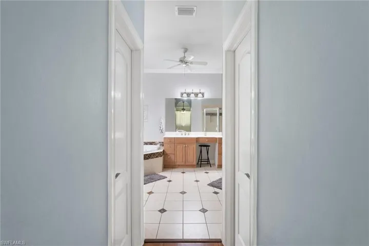 Hall with ornamental molding, sink, and light tile patterned flooring