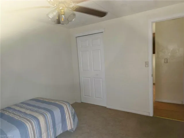 Bedroom featuring light colored carpet, a ceiling fan, and a closet