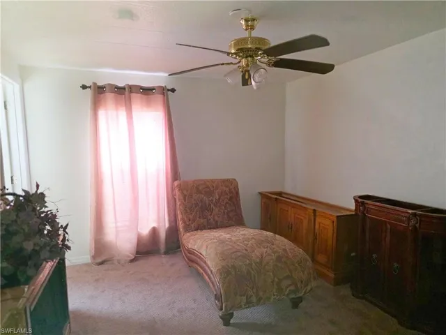 Sitting room featuring light colored carpet and a ceiling fan