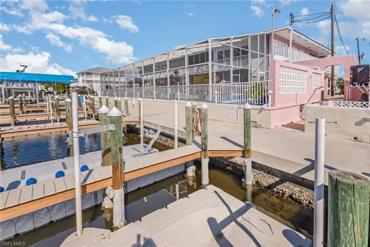 Dock area featuring a water view, boat lift, and screen enclosure