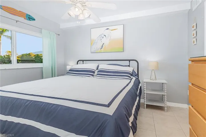 Tiled bedroom featuring ceiling fan and baseboards