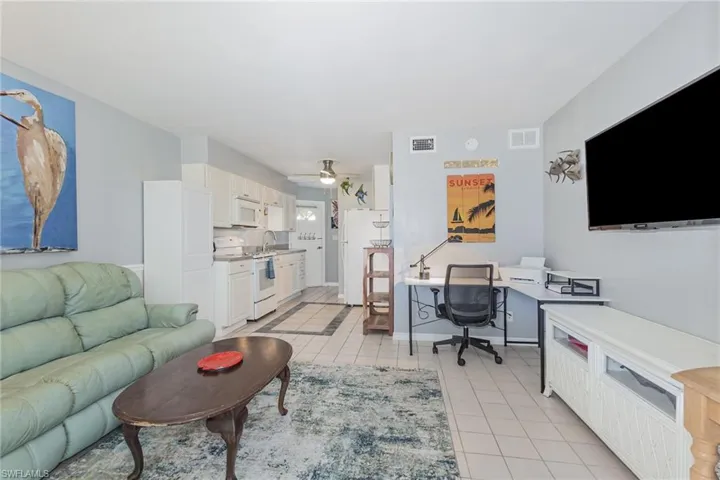 Living area with an office area, light tile patterned flooring, and a ceiling fan