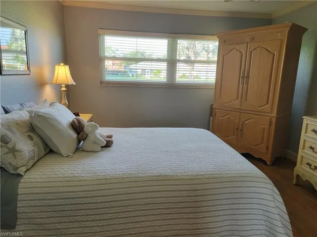 Bedroom featuring dark hardwood / wood-style floors, multiple windows, and crown molding