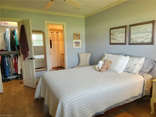 Bedroom featuring dark wood-type flooring, a closet, ceiling fan, and ornamental molding