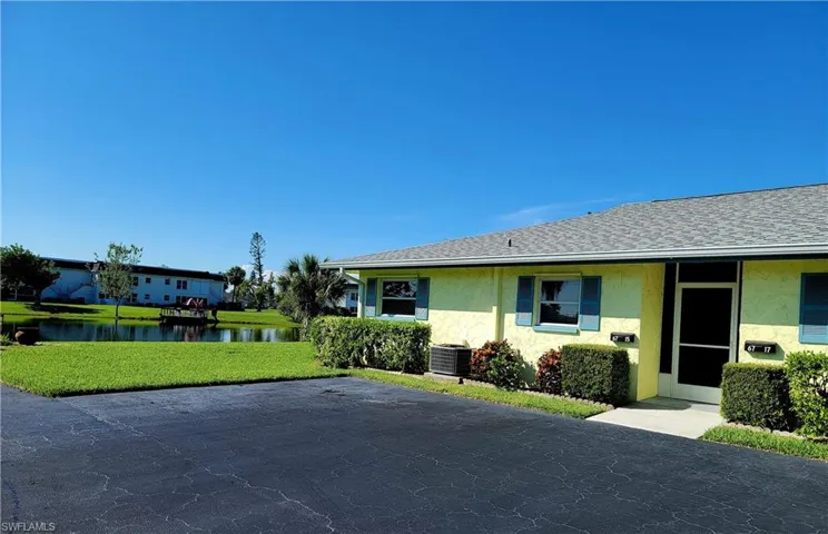 View of front of house featuring a front lawn, central AC unit, and a water view