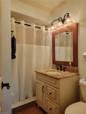 Bathroom with vanity, toilet, and ornamental molding