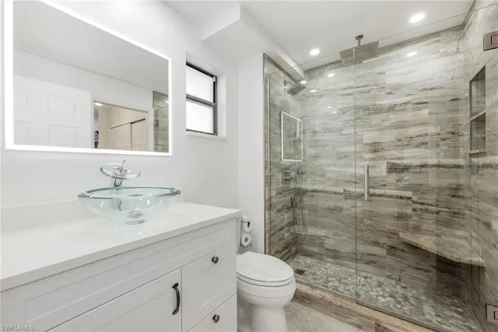 Bathroom with vanity, a shower with shower door, and toilet