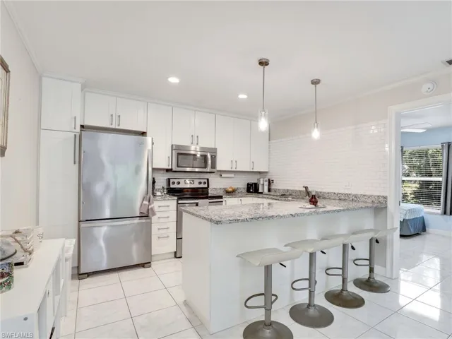 Kitchen featuring kitchen peninsula, tasteful backsplash, stainless steel appliances, pendant lighting, and light tile floors