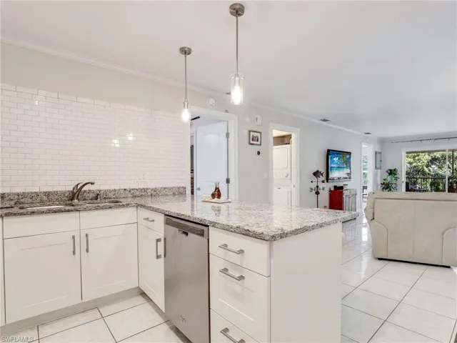 Kitchen with kitchen peninsula, stainless steel dishwasher, white cabinets, light tile floors, and pendant lighting