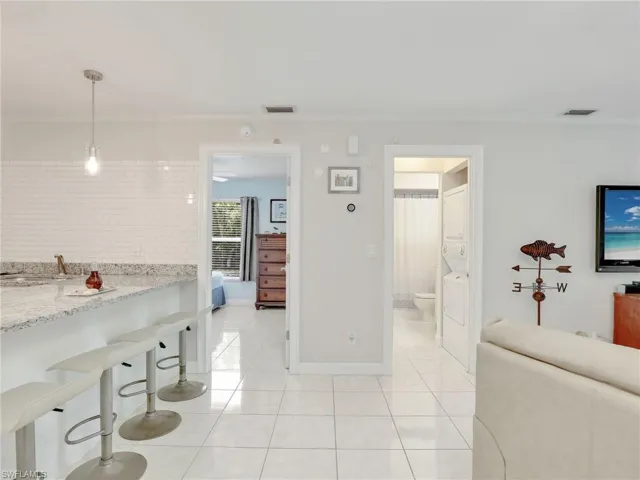 Kitchen with hanging light fixtures, light stone counters, a kitchen bar, and light tile floors