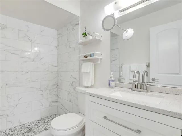 Bathroom featuring a tile shower, oversized vanity, and toilet