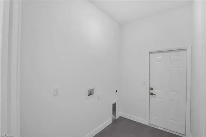 Laundry area with hookup for a washing machine, electric dryer hookup, and dark tile patterned flooring