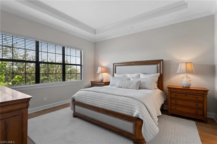 Bedroom featuring a raised ceiling, crown molding, and wood finished floors