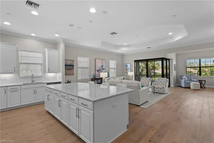 Kitchen with white cabinetry, ornamental molding, plenty of natural light, light wood-style flooring, and light stone counters