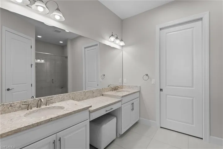 Bathroom featuring a shower stall, light tile patterned floors, and double vanity