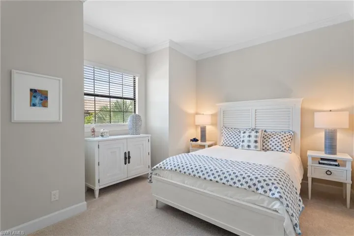 Bedroom with crown molding and light colored carpet