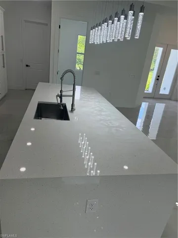 Kitchen featuring sink, pendant lighting, french doors, and a kitchen island with sink