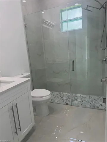 Bathroom with tile patterned floors, toilet, vanity, and an enclosed shower