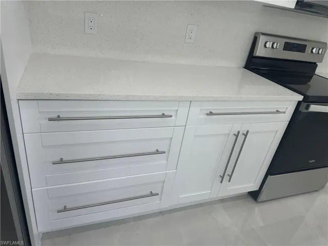 Room details with white cabinets and stainless steel range with electric cooktop