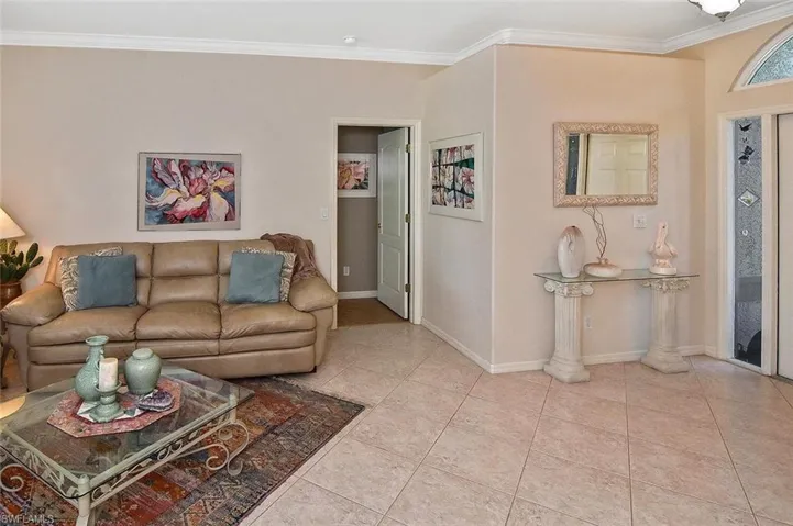 Living room with crown molding and light tile patterned floors