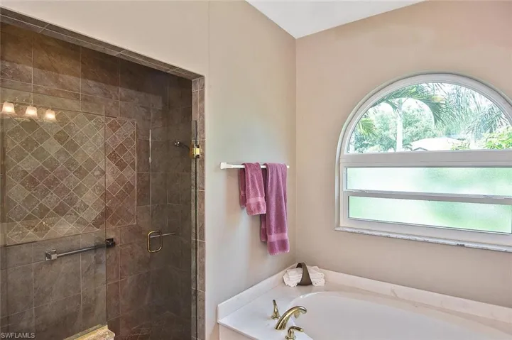 Bathroom with a bath, healthy amount of natural light, and a stall shower