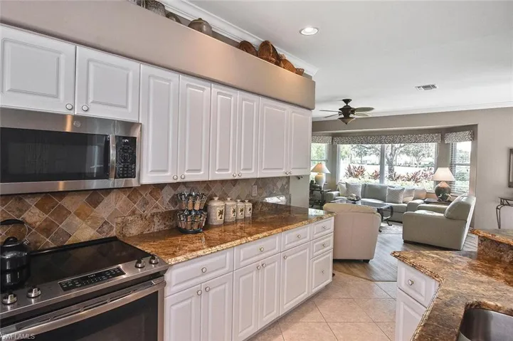 Kitchen with stainless steel appliances, a ceiling fan, tasteful backsplash, white cabinetry, and recessed lighting