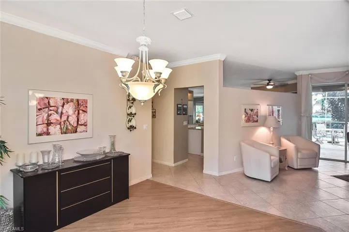 Dining room with crown molding, a chandelier, ceiling fan, and light tile patterned flooring