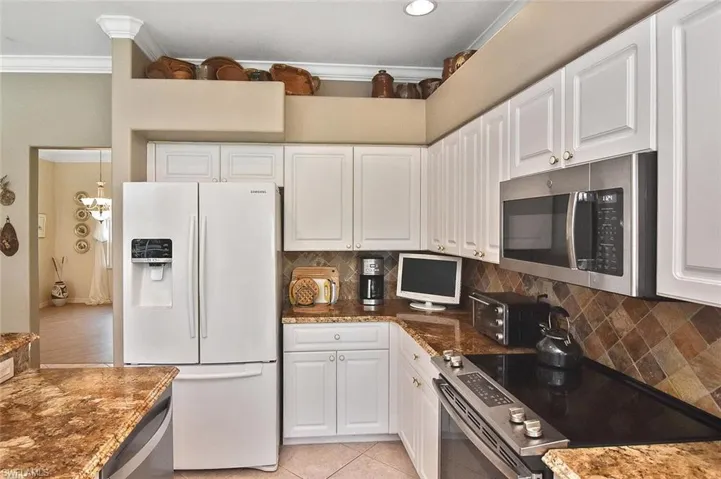 Kitchen with appliances with stainless steel finishes, ornamental molding, white cabinets, decorative backsplash, and recessed lighting