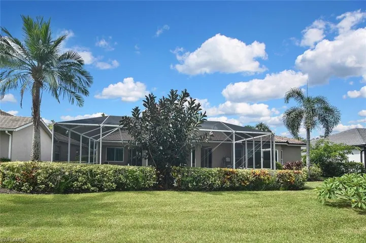 Rear view of house featuring stucco siding, a yard, and a lanai
