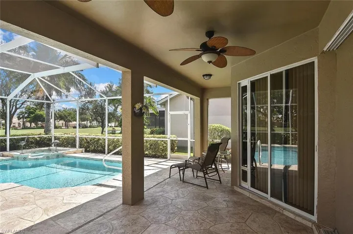 View of pool featuring ceiling fan, a patio area, a pool with connected hot tub, and glass enclosure