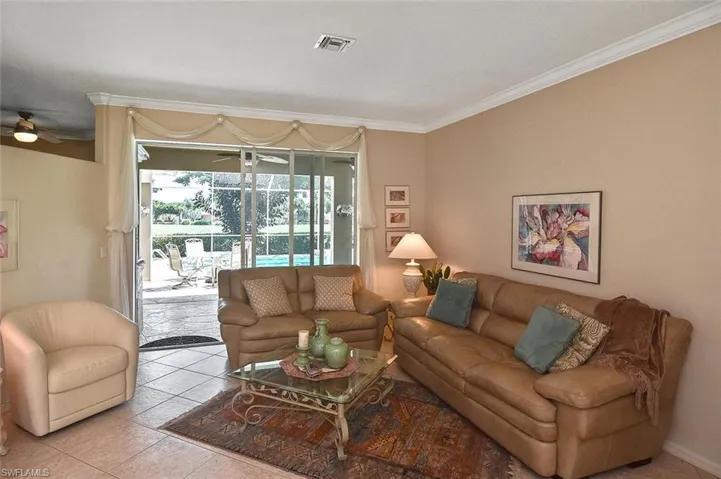 Living area with ornamental molding, a ceiling fan, and light tile patterned floors
