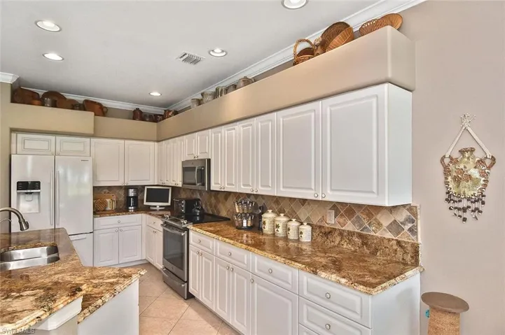 Kitchen featuring stainless steel appliances, white cabinets, dark stone countertops, decorative backsplash, and recessed lighting