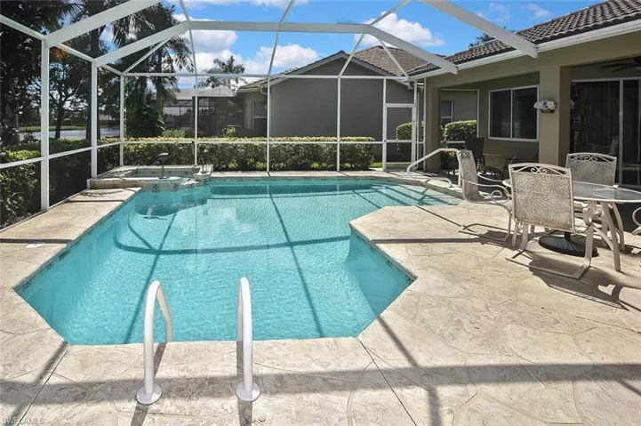 View of pool featuring a patio, a pool with connected hot tub, and glass enclosure