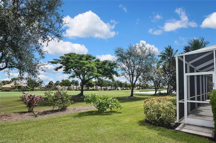View of green lawn with a water view, glass enclosure, and golf course view