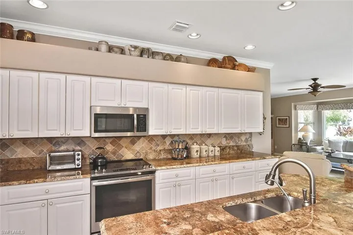Kitchen featuring stainless steel appliances, crown molding, white cabinets, backsplash, and recessed lighting