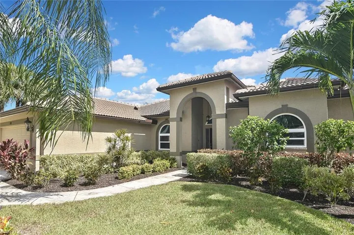 Mediterranean / spanish home featuring a tile roof, an attached garage, stucco siding, and a front lawn