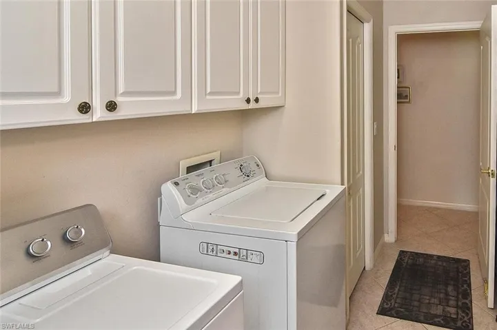 Washroom with washer and clothes dryer, light tile patterned floors, and cabinet space