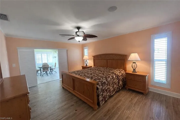 PRIMARY Bedroom featuring dark wood finished floors, ornamental molding, and ceiling fan