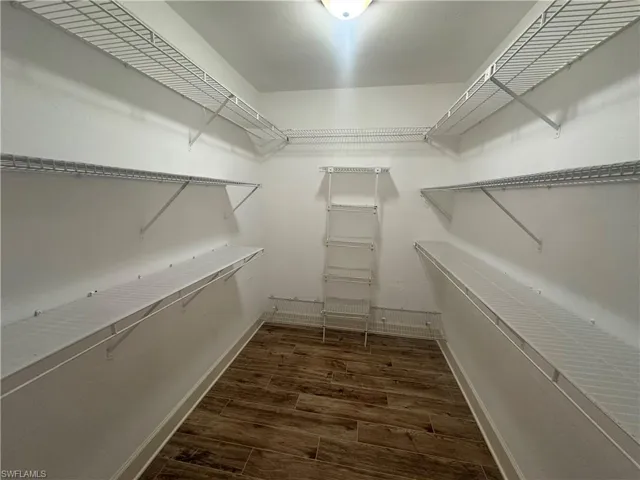 Primary Walk in closet featuring dark wood finished floors