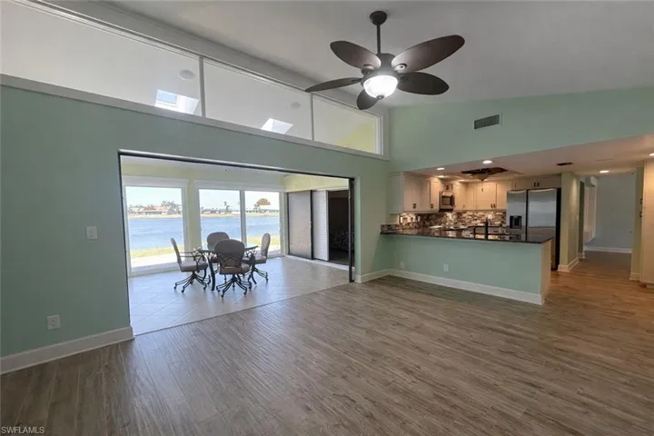 Living area with lofted ceiling, a water view, dark wood-type flooring, and a ceiling fan