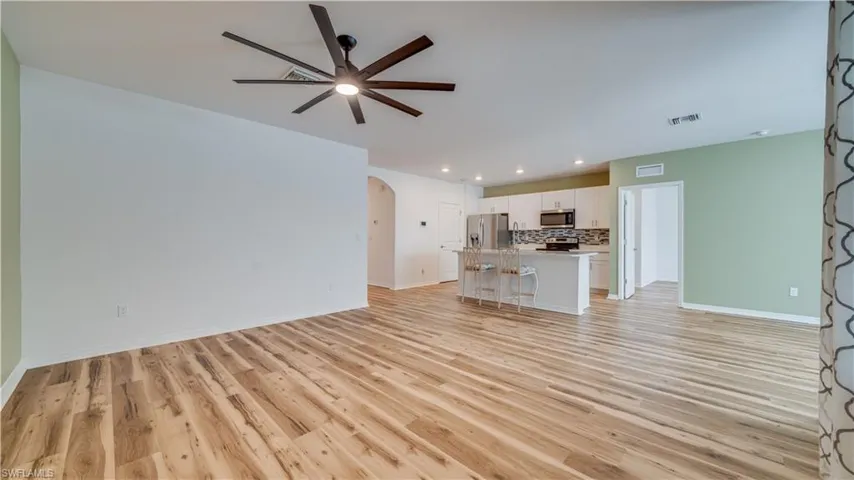 Unfurnished living room featuring arched walkways, light wood finished floors, a ceiling fan, and recessed lighting