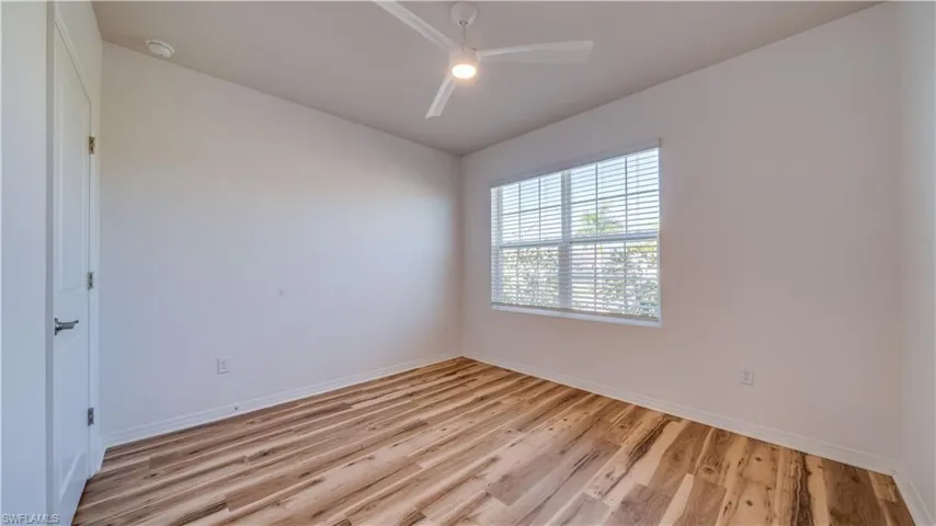 Spare room featuring light wood-style flooring, ceiling fan, and lofted ceiling