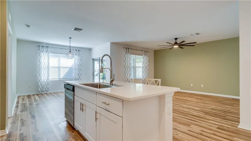 Kitchen featuring white cabinetry, light wood-type flooring, open floor plan, and pendant lighting