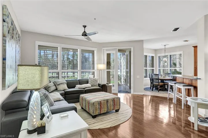 Living room with a ceiling fan, a healthy amount of sunlight, visible vents, and wood finished floors
